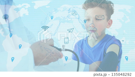 Measuring boy blood pressure with cuff and gauge in clinic, with world map, icons, copy space Measuring boy blood pressure with cuff and gauge in clinic, with world map, icons, copy space 135048292