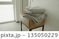 Stack of folded grey towels on wooden table in modern bathroom. Clean and organized interior with soft textiles and minimalistic decor. 135050229