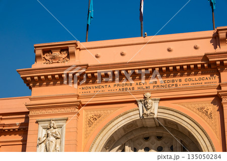 Cairo Museum at Tahrir Square features a grand facade with large windows and intricate architectural details. A stone sphinx sculpture is visible in the foreground Cairo Museum at Tahrir Square features a grand facade with large windows and intricate architectural details. A stone sphinx sculpture is visible in the foreground 135050284