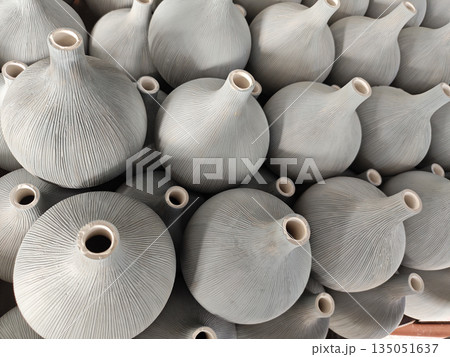 Unfinished grey clay vase pile showing rustic craft texture feeling authentic and raw with traditional handmade pottery production stacking together in workshop waiting for firing process 135051637