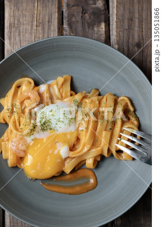 乗せてある温玉を崩した平麺の濃厚エビクリームパスタ 135051866