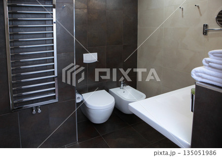 The bathroom is in the hotel room. Stylish dark tiles on the walls. The concept of recreation and travel. The bathroom is in the hotel room. Stylish dark tiles on the walls. The concept of recreation and travel. 135051986