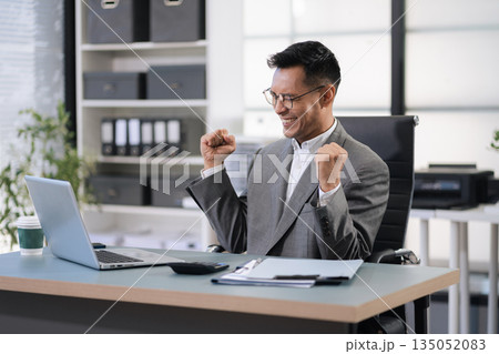 Happy male businessman celebrating success, raising hands in excitement 135052083