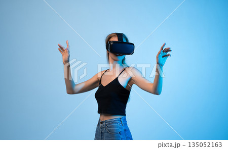Woman wearing virtual reality headset and interacting with digital space using both hands, immersive VR technology and future interface concept Woman wearing virtual reality headset and interacting with digital space using both hands, immersive VR technology and future interface concept 135052163
