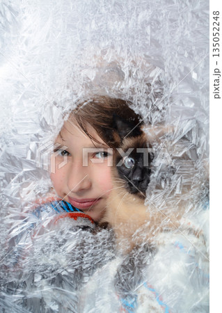 Beautiful thoughtful boy and his cat looking through frozen glass. Winter portrait. 135052248