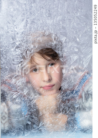 Handsome thoughtful boy looking through frozen glass. Winter portrait. Handsome thoughtful boy looking through frozen glass. Winter portrait. 135052249