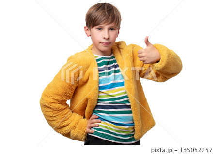A boy in a yellow fluffy jacket and a striped shirt. He shows the sign of class. A boy in a yellow fluffy jacket and a striped shirt. He shows the sign of class. 135052257