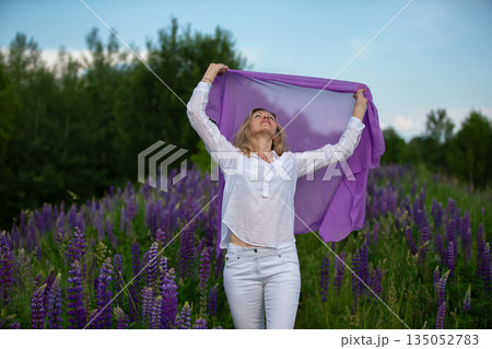 Woman enjoying a sunny day in a lush purple flower field Woman enjoying a sunny day in a lush purple flower field 135052783
