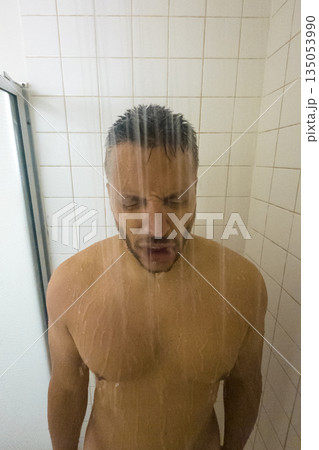 A man is standing in a shower with his head under the water A man is standing in a shower with his head under the water 135053990