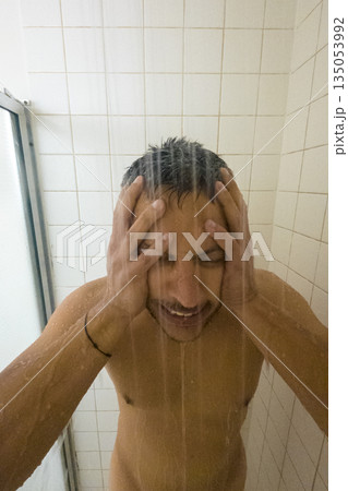 A man is in the shower with his hands on his head 135053992