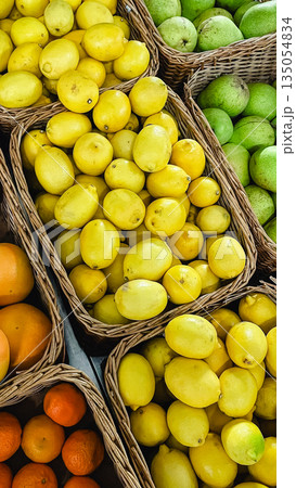 Abundance of fresh lemons, tangerines and green pears in wicker baskets at a local farmer market 135054834
