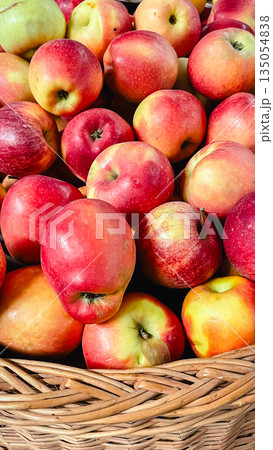 Close-up of fresh ripe red and yellow apples in a wicker basket at a local market or grocery store 135054838