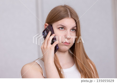 Young woman engaged in a phone conversation in a modern indoor setting 135055029