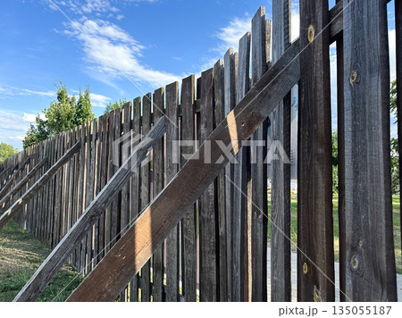 A rustic wooden fence under a blue sky in a natural setting. 135055187