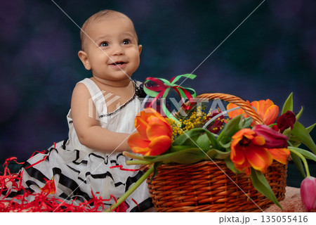 Funny little one year old girl with flowers. She is smiling. 135055416