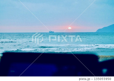 車のフロントガラス越しに見える海岸の夕日 135055950