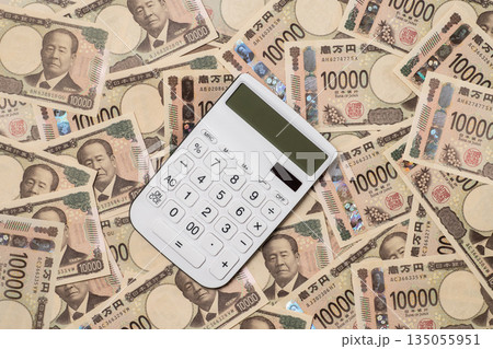 敷き詰められた多数の一万円札と電卓 135055951