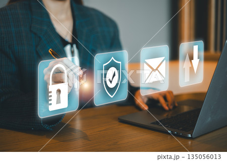 A business professional interacts with digital security icons on a laptop, symbolizing data protection and secure communication. 135056013