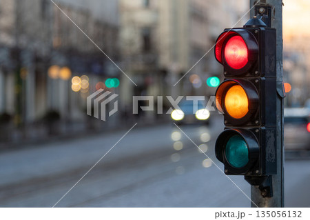 Traffic signal shows red, yellow, and green lights on a busy street in the evening Traffic signal shows red, yellow, and green lights on a busy street in the evening 135056132