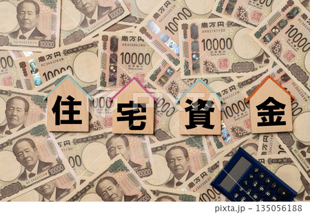 住宅資金の文字と家形のプレートと敷き詰められた一万円札 住宅資金の文字と家形のプレートと敷き詰められた一万円札 135056188