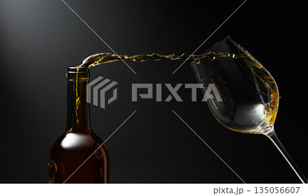 White wine of rich amber color being poured into a glass. White wine of rich amber color being poured into a glass. 135056607