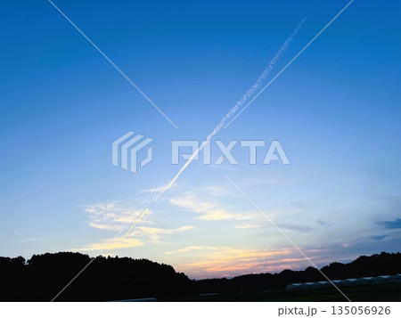 長い飛行機雲が横切る夕焼け空 | ドラマチックな夕陽 135056926