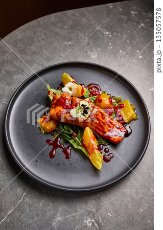 Gourmet Grilled Salmon with Citrus and Pomegranate Garnish on Dark Plate, Elegant Food Presentation Concept 135057578