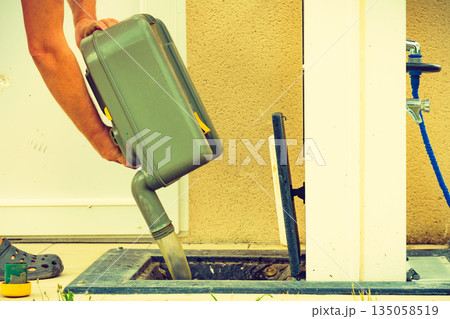 Man emptying caravan tank toilet cassette in dump station. Man emptying caravan tank toilet cassette in dump station. 135058519