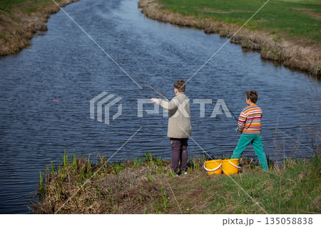 Boys children catch fish near the river. View from behind. Boys children catch fish near the river. View from behind. 135058838