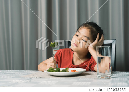 Little cute kid girl refusing to eat healthy vegetables. Children do not like to eat vegetables. Little cute kid girl refusing to eat healthy vegetables. Children do not like to eat vegetables. 135058985
