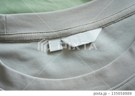Close up of blank white clothing care label on white shirt fabric background. 135058989