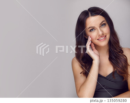 Beautiful brunette smiling woman with a long hair on a grey isolated background with a free copy space. 135059280