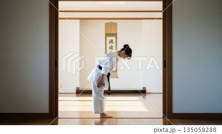 道場の入り口で凛とした姿で立礼をする空手着の日本人女性 135059288