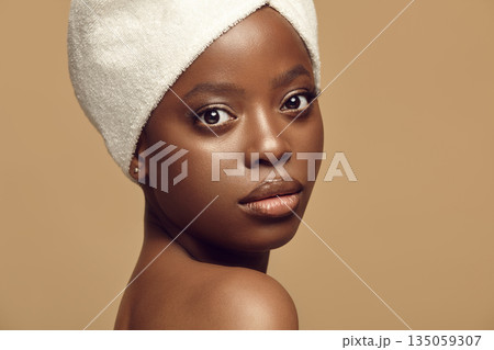 Beautiful African girl in hair drying towel looks to camera. 135059307