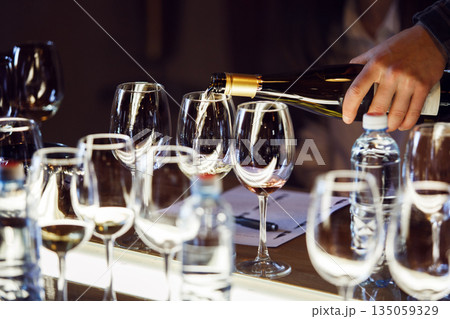 Close-Up View of White Wine Being Poured Into Elegant Glasses for Tasting Event Close-Up View of White Wine Being Poured Into Elegant Glasses for Tasting Event 135059329