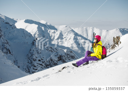Female Hiker Taking Break on Snow-Covered Mountain Slope During Winter Female Hiker Taking Break on Snow-Covered Mountain Slope During Winter 135059337