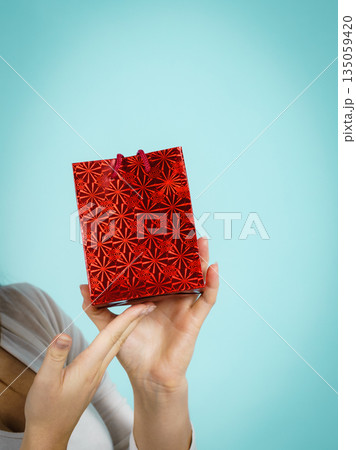 Woman holds red gift bag in hand Woman holds red gift bag in hand 135059420