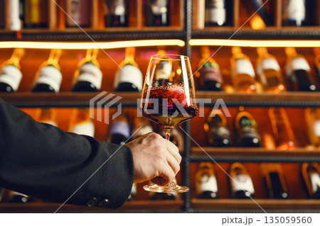Swirling Dark Red Wine with Cellar Bottles 135059560