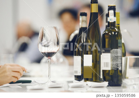 Different Bottles on Blurred People Background, Start of Sommelier Event for Various Wine Tasting. Different Bottles on Blurred People Background, Start of Sommelier Event for Various Wine Tasting. 135059586