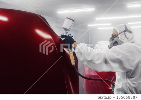 Professional car painter in chamber paints automobile bonnet. Professional car painter in chamber paints automobile bonnet. 135059587