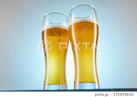 Yellow alcoholic fizzy drink, brew fills glasses to brim. 135059650
