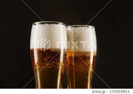 Golden brew with foam, bubbles filling tall glasses. Golden brew with foam, bubbles filling tall glasses. 135059651