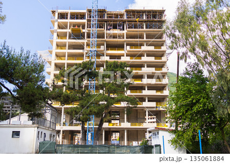 Construction site with unfinished concrete building. Urban infrastructure, civil engineering, and ongoing construction in suburban neighborhoods. 135061884