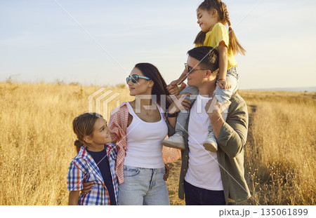 Happy family enjoying summer sunset outdoors, standing together in rural landscape Happy family enjoying summer sunset outdoors, standing together in rural landscape 135061899