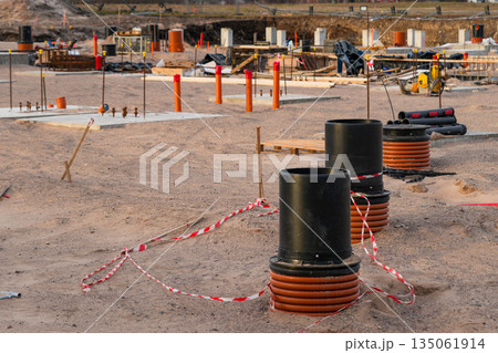 Foundation construction site with underground communications wells and pipe outlets in sand 135061914