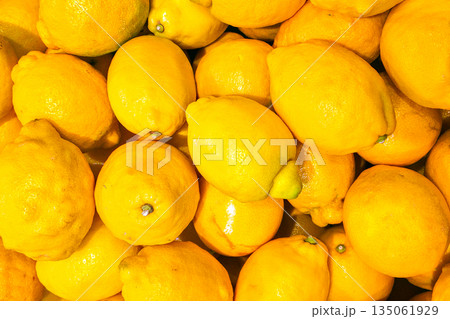 Fresh ripe lemons background, bright yellow citrus fruits stacked together in a natural market display Fresh ripe lemons background, bright yellow citrus fruits stacked together in a natural market display 135061929