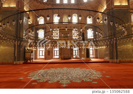 Beautiful interior of Yeni Cami Mosque with large circular chandeliers, red carpet and stained glass windows in Eminonu, Istanbul 135062588