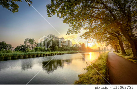 Behold the Serene Sunset That Casts Its Glow Over a Beautiful and Tranquil Riverbank Landscape 135062753