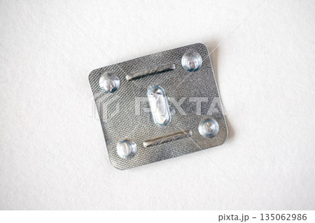 Empty metal used blister pack for one tablet, isolated on white background. Metal capsule blister top view. 135062986