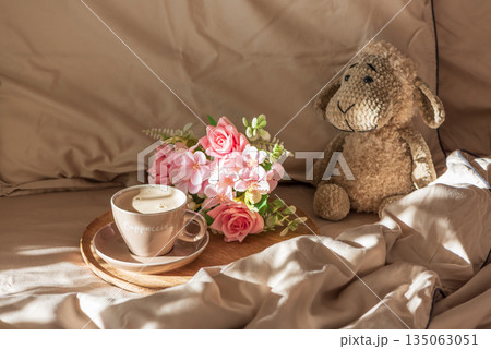 Cappuccino with Flowers and Plush Sheep on Cozy Bed under Morning Sunlight 135063051